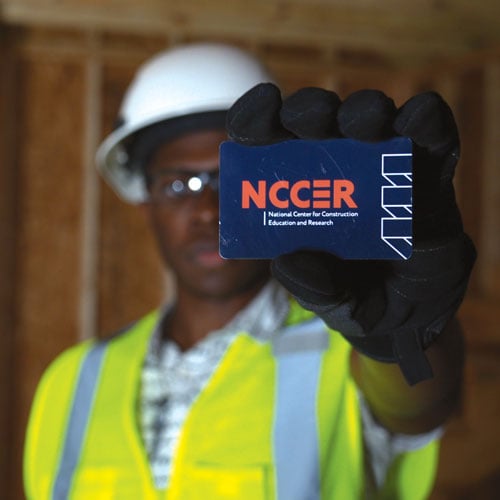 A man holds an NCCER wallet card toward the camera.