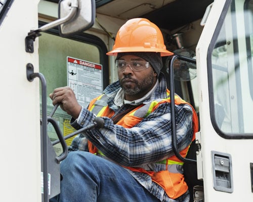 A crane operator holds a lever inside the cabin of a crane.